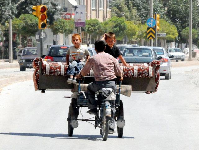  tekerlekli bisiklette tad kanepenin stne ocuklarn oturtan bir baba objektife byle yansd