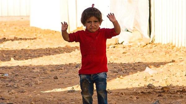 Fotoraf makinesini silah sanp ellerini kaldran Suriyeli kk kzn fotorafnda bir ocuun gzlerindeki sava izleri grlyor