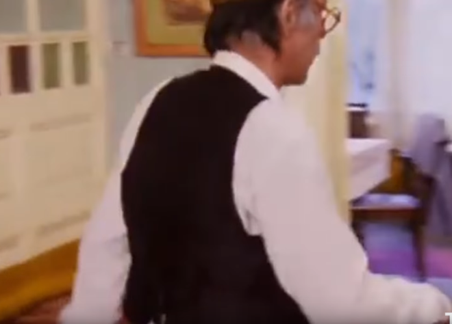 "Neeli Gnler" filminin bir sahnesinde Mnir zkul duvarda olmayan prize tnn fiini takyor.