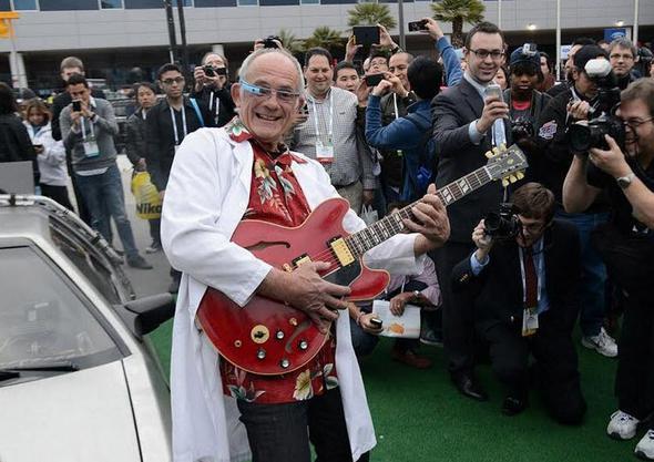 Gelecee Dn serisinin lgn doktoru Emmet Brown yannda Delorean ve elinde gitar ve gznde Google'n akll gzlyle...