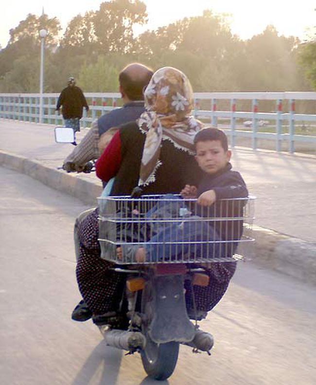 Arka tarafna yaptrlan sepette tanan ocuun bulunduu motosiklette, bir aile seyahat ediyor. Bir yandan srcye tutunan anne, kucandaki bebee de hakim olmaya alyor. Ltfen bu aileyi rnek almayn!