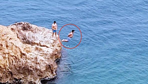 Antalya’da iki gencin �l�m oyunu kameralara yans�d�. Konyaalt� sahilinde elleri ve ayaklar�na arkada�� taraf�ndan plastik kelep�e tak�lan gen�, kayal�klardan atlay�p k�y�ya kadar y�zd�.