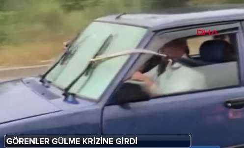 Grntlerde yamur altnda hzla ilerleyen otomobilin bozuk sileceklerinin arka koltukta oturanlar tarafndan iple ekilerek kontrol edildii grlyor.