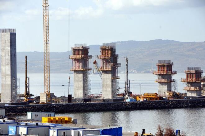 Denize bat�r�lan kule kesonlar� �zerine konulmaya devam edilen bloklarla k�pr� ayaklar�, ilerleyen g�nlerde y�kseltilecek. T�m bloklar�n konulmas�n�n ard�ndan T�rk bayra��n�n renklerini alacak, 318 metrelik k�pr� kuleleri tamamlanacak. �anakkale Deniz Zaferi'nin y�l d�n�m� olan 18 Mart'� temsil eden 318 metre y�ksekli�indeki kulelerin �st k�sm� da Seyit Onba��'n�n �anakkale Sava��'nda namluya s�rd��� top mermisini temsil edecek �ekilde olacak.