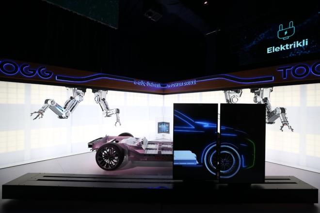 TEKNOLOJK DNMN NCLERNDEN BR OLACAK  <br>  te yandan TOGG'dan yaplan aklamaya gre, TOGG'un kuruluundan bugne geen 18 ayda ald mesafeyi ve Trkiye?de teknolojik dnme nasl nclk edecei paylalacak.    Resmi kuruluu 28 Haziran 2018'de gerekleen ve kuruluundan 18 ay sonra 3 boyutlu ilk modelini ve bir konsept aracn gn na karan TOGG, Trk Otomotiv endstrisinin kalbi olan Marmara Blgesi?nde kurulacak fabrikasnn temelini 2020 ylnda atacak. 2030 ylna kadar ise fikri ve snai mlkiyet haklar tamamen kendisine ait bir ortak e-platform zerine 5 farkl model retecek.