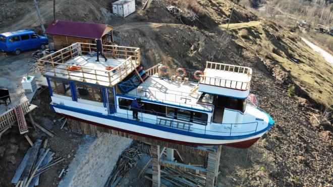 Maliyetin 200 bin TL?ye ulatn belirten Turan Zafer?in olu Emirhan Zafer ise ?Projemizde kafe blm yapmamz gerekiyordu. Biz de bu vadiye nasl bir hareket getiririz, Karadeniz?de bir ilki yapmak adna tekne aratryorduk. Karadeniz?de tekneler bir hayli pahal. Bu teknemizi Giresun ili Tirebolu ilesinde bir aabeyimizden bulduk. Tekneyi balk ekmek satmak iin kullanyordu. Kendisiyle grtk anlatk aldk. Tirebolu?dan Akaabat Limanna getirdik, oradan da TIR yardmyla buraya kadar getirdik. Teknenin daha ncesini aratrdm ilk olarak stanbul?da tur teknesi olarak kullanlyordu. Nasip Dzky?n tepesineymi. Dolaysyla teknemiz stanbul Boazndan Dzky?n yaylasna gelmi oldu. Maliyeti biraz fazla oldu diyebiliriz. Yerine oturmas hepsi yaklak 200 bin TL?ye mal oldu. TIR srcs bize sizin yaptnz tam bir delilik. ?Beni de kendinize uydurdunuz? dedi. ?Bu yollara mmkn deil byle bir tekne kartamazsnz? dedi. Biraz zahmetli oldu ama sonunda baarabildik. evremizden bize olmaz yapamazsnz; oraya tekne mi olur diye sylenenler oldu. Karadeniz insannn inad vardr ya biz de inat olduk. Alt zemin tasarmn, yerletirmesini tamamen kendimiz yaptk. lk planmz yatay koymakt sonradan daha pahal cezbedici bir ey olsun dedik ve dik bir ekilde koyduk? ifadelerini kulland.