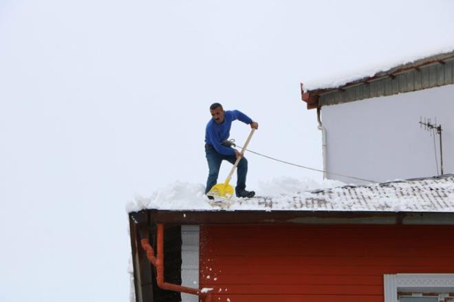 Hakkari'de, youn kar yann ardndan binalarn atsnda biriken karlarn temizlenmesi iin iiler, bellerine taktklar halatla temizlik almas yrtyor.