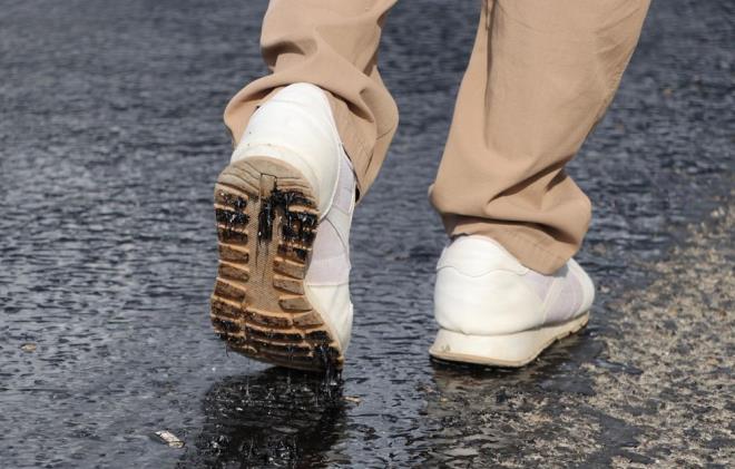 AYAKKABILAR ERYEN ASFALTA YAPITI    Srcler, aralarn zifte bulatrmamak iin yolun kuru blmlerinden gitti. Asfaltta yrmekte glk yaanrken, ayakkablar eriyen asfalta yapt.