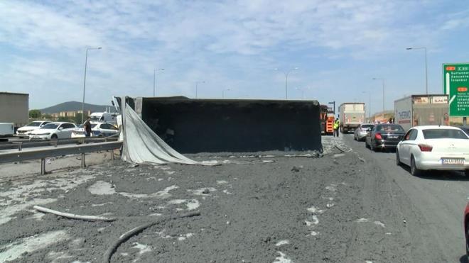 Kaza nedeniyle yan yatan hafriyat kamyonundaki imento yola dkld.