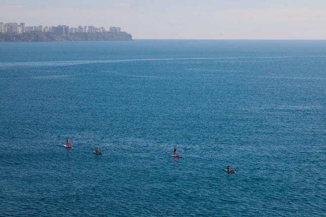 Su sporlar yapan turistler kanolaryla denizin ve scak havann keyfini srerken falezlerin bulunduu yerdeki kayann zerinden de bir grup gen denize atlayp yzd.
