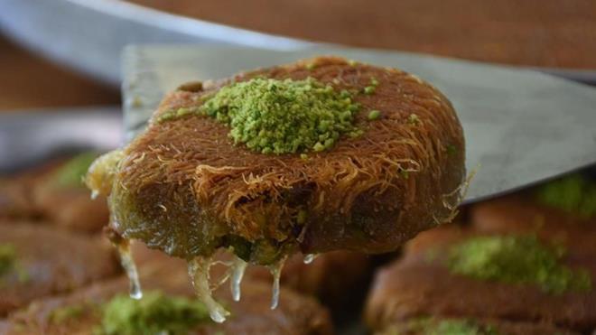 KADAYIF NASIL YAPILIR?    Kadayf yaplmas iin nce tepsi altna kat ya katlm pekmez srlr. Bu tereya olursa daha makbul ve lezzetli olur. Daha sonra hamurdan yaplm tel burmann iine ceviz krnts ile tel kadayf doldurulup sarldktan sonra tepsiye srasyla koyulur. Sonra dizilmi olan i kadayf zerine inceltilmi ya dklp atee koyulur.    Ate, tepsi altn komple sararak yanmaldr. Kadayfn ate taraf pien yz evrilmeden nce tepsi iindeki ya bir kaba szlr. Sonra alt yz evrilir. Dier taraf piirilmeye koyulur. Piirildikten sonra tepsi iindeki ya iyice szlr, ateten alnp zerine, hazrlanm olan kadayf iresi dklr. Yemee hazr duruma getirilir.