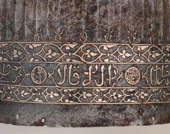 Hakan Y�lmaz, ayr�ca mi�ferin �zerindeki g�m�� kakma Arap�a ana kitabede Osman Gazi'nin kendisini <strong>"Sult�n�'l-a'zam" (B�y�k Sultan) ve "H�n�'l-mu'azzam" (Ulu Han)</strong> unvanlar�yla tan�tt���n�, arka y�z�ndeki madalyonda ise <strong>"N�s�r�'d-d�n 'Osm�nSult�n"</strong> ifadesinin yer ald���n� a��klad�. Bu unvanlar�n, Osman Gazi'nin ba��ms�z bir sultan olmad��� y�n�ndeki kurgusal akademik iddialar� tamamen ��r�tt���n� belirtti.