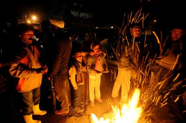 Erci'te yklan binalarn arasndaki atein etrafnda bekleyen depremzedeler. (25 Ekim 2011)