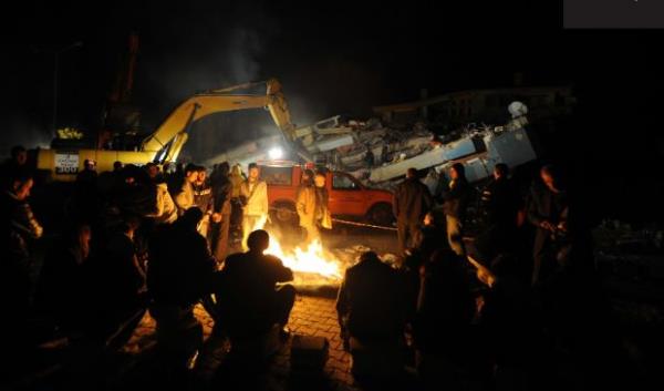 Depremzedeler Erci'te yklan binalarn arasnda ate yakm etrafnda oturuyor (29 Ekim 2011)