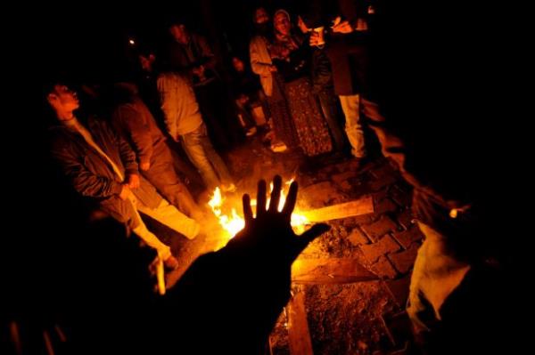 Depremzedeler Erci'teki yklan binalarn arasnda ate yakmlar. (30 Ekim 2011)