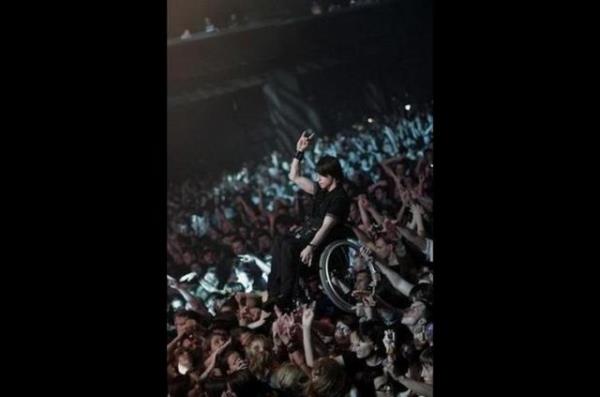 Kalabalk, konserde tekerlekli sandalyeli genci, sahneyi rahat grmesi iin havaya kaldrrsa