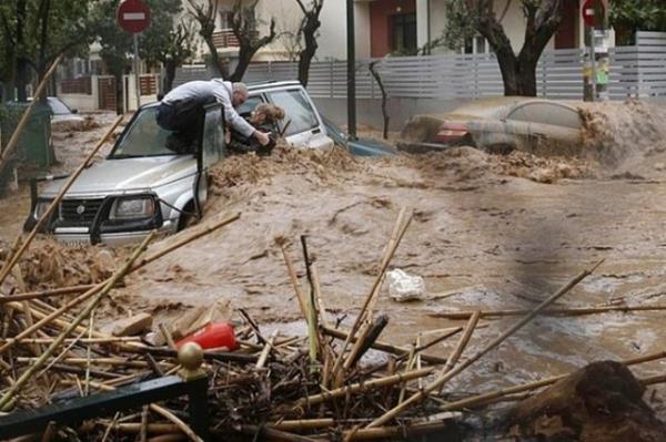 Atina'daki selde sulara kaplm bir kadn kurtarmaya alan adam
