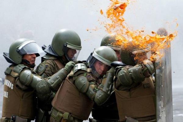 <p><b>Mart</b></p>  �ili'nin Santiago kentinde ��rencilerle ��kan �at��malarda kendilerini, f�rlat�lan nesnelerden korumaya �al�san �evik kuvvet polisi