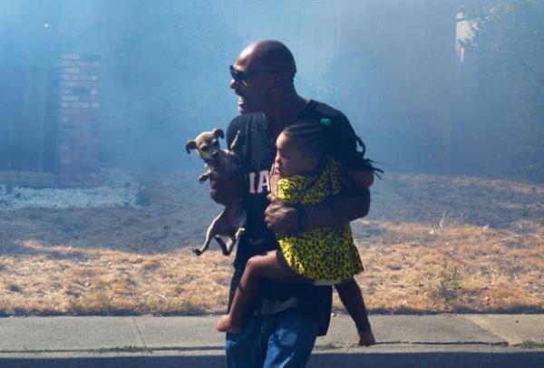 <p><b>A�ustos</b></p>  LaRue Montgomery, Fairfield California'da ��kan yang�nda 2 ya��ndaki ye�eni Brianna ile k�pe�ini evinden ��kar�rken.