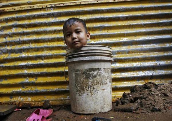 Hindistan'n Chennai ehrindeki barakalarnn nnde ykanmak iin annesini bekleyen kk bir ocuk, bir yandan da ykanaca kovayla oyun oynuyor. Hindistan