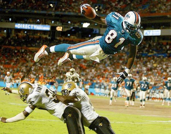 Dolphins formas giyen Randy McMichael, Saints savunmacs Michael Hawthorne ve Mel Mitchell?in zerinden touchdown iin atlarken...