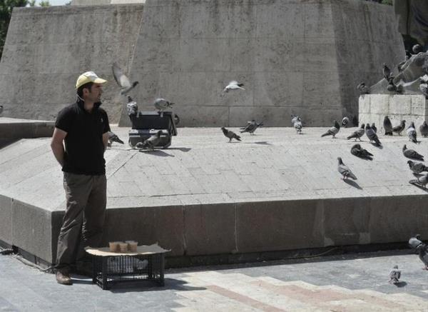 Ku yemi satarak geimini salayan bir seyyar satc da gnn en scak saatlerinde apkasyla gneten korunmaya alyor.