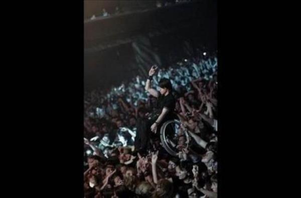 Kalabalk, konserde tekerlekli sandalyeli genci, sahneyi rahat grmesi iin havaya kaldrrsa.