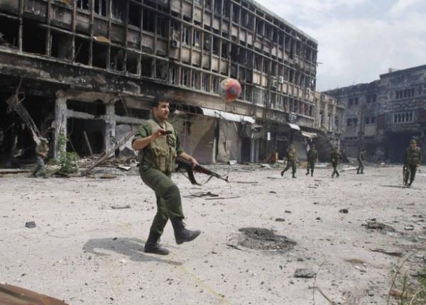 Suriyeli askerler Humus'ta bir mahellede top oynuyor.