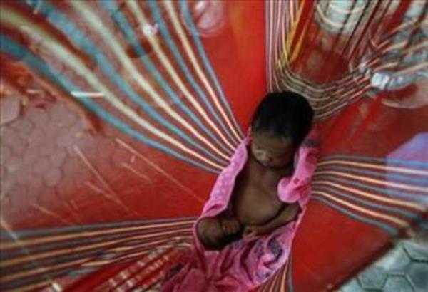 Hintli kk ocuk, ailesinin sokaa kurduu salncakta uyuyor.