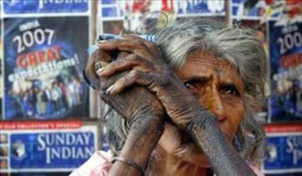 Hindistan'da yeni yl afilerinin nnde oturan evsiz bir kadn.