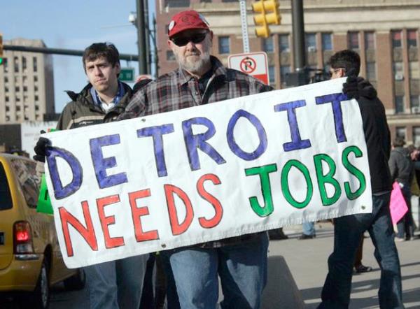 Krizi protesto eden bir ii 'Detroit'in ie ihtiyac var" yazl pankart tayor.