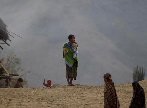 Yansi Ky'nden bir Naga erkei, sarnd battaniye ile hem kendisini, hem de kucandaki bebei scak tutmaya alyor