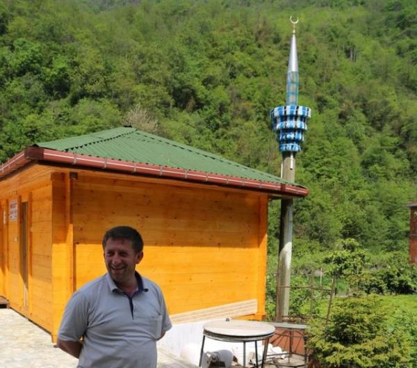 Tesisin yan tarafndaki bahede atl durumda bulunan elektrik direine araba lastiklerini geirip LED yla donatan ve minare eklini veren iletme sahibi, daha sonra 200 metre tedeki ahap mescidi de buraya tad.