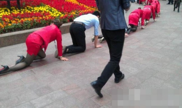 Chongqing blgesindeki Yuzhong ehrinde bir grup niformal alan dizleri zerinde yry yaparken grlyor.