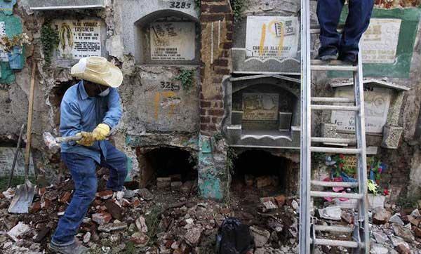 Eline tokmak alan bir mezar yetkilisi, blmler halindeki mezarln baz ksmlarn vurarak krmaya alyor.