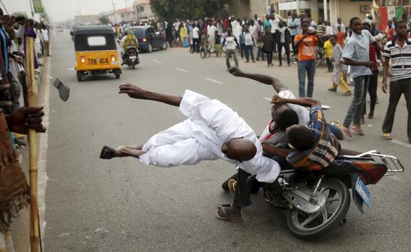 Nijerya'da bakan aday olan Muhammadu Buhari'nin destekileri, baka bir destekiye motosikletle arparken. (31 Mart)